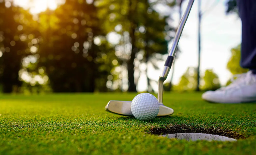 Golfer about to putt the ball into a hole.